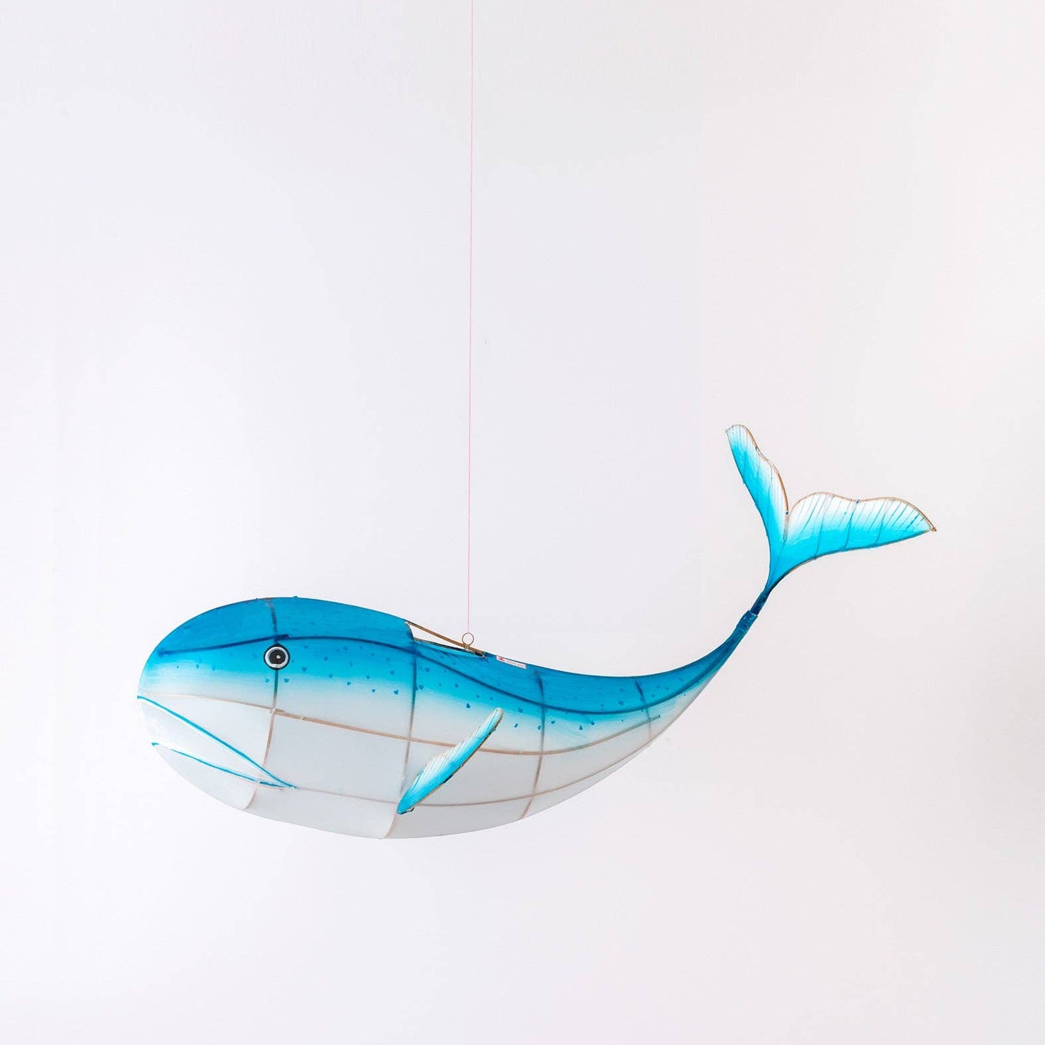 Blue whale-shaped kite on a white background