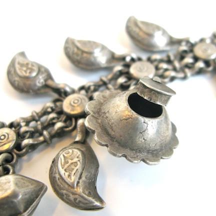 Silver necklace with leaf shaped charms and geometric pendant, close up on chain