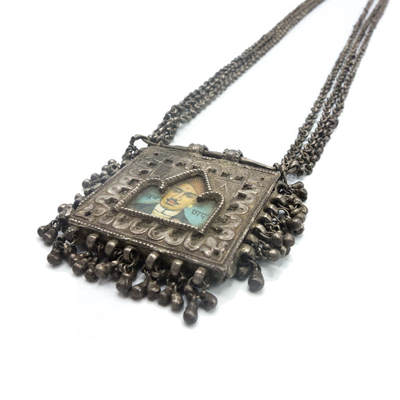 Silver necklace with a picture of a man in the center and small bell charms