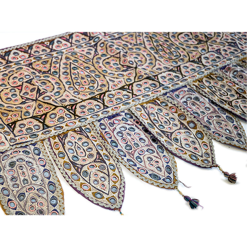 Colorful Indian door hanging with pieces of mirror, multicolored embroidery and tassels. Close up
