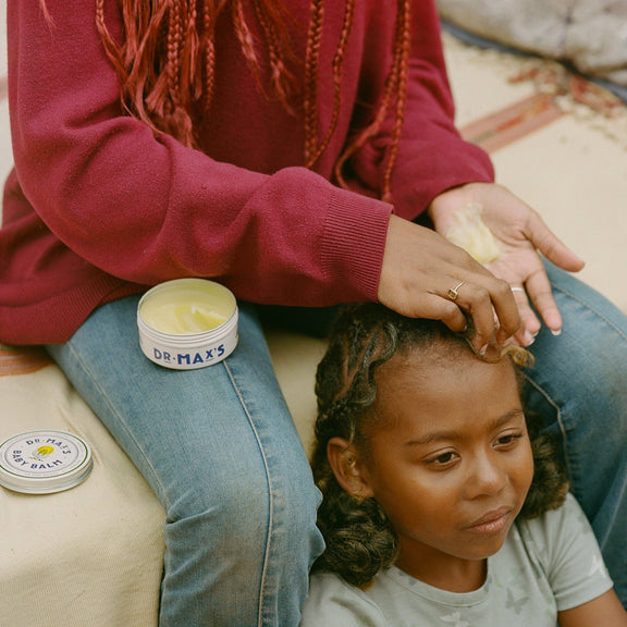Person applying product to a child's hair with Dr. Max's product visible