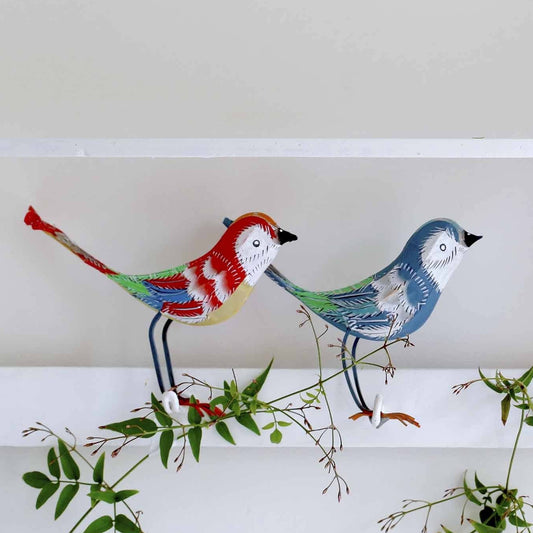 Two colorful bird figurines on a branch against a white background
