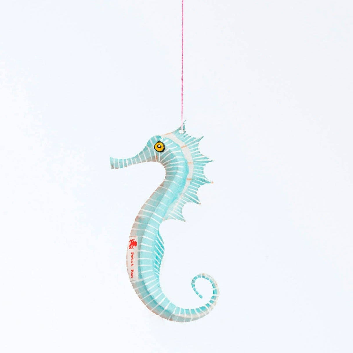 Decorative seahorse hanging on a string against a light blue background