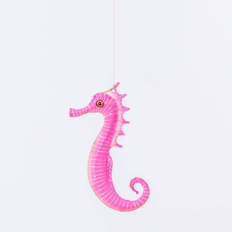 Pink seahorse toy hanging against a white background
