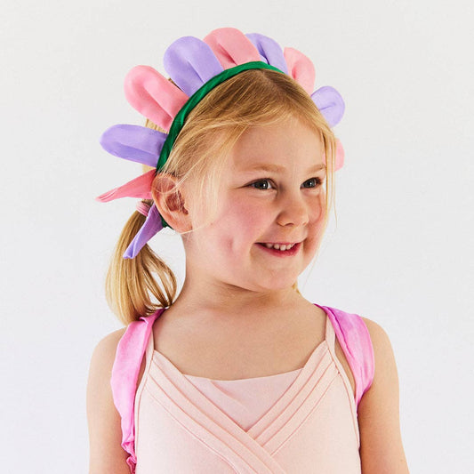 Young girl wearing a colorful headband with pink, purple, and green accents on a white background