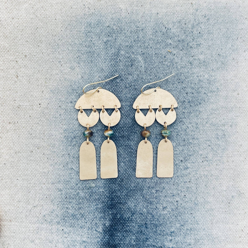 Pair of gold earrings with hanging elements on a textured blue background