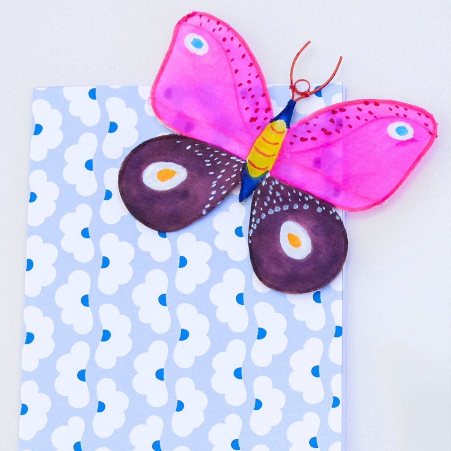 Butterfly-shaped object on a notebook with a blue and white pattern