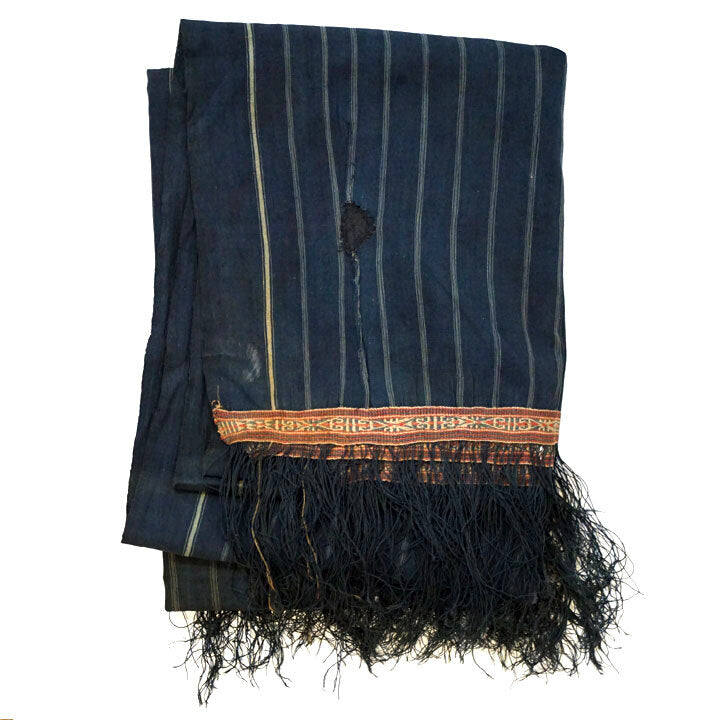 Cotton indigo colored batak with subtle stripe pattern, orange trim and black tassels. Folded