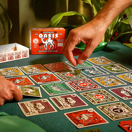 Playing cards with colorful designs on a green tablecloth, with a hand reaching for a card.