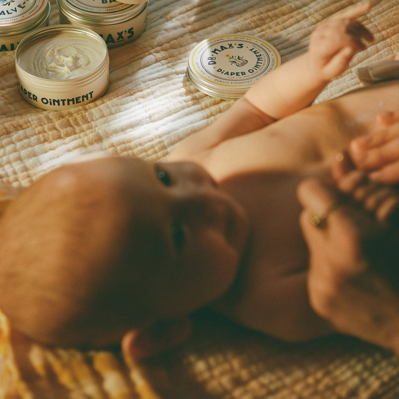 Baby being cared for with Dr. Max's diaper ointment on a textured surface
