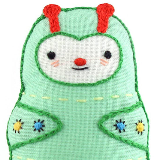Toy plush character with green outfit and red antlers on a white background