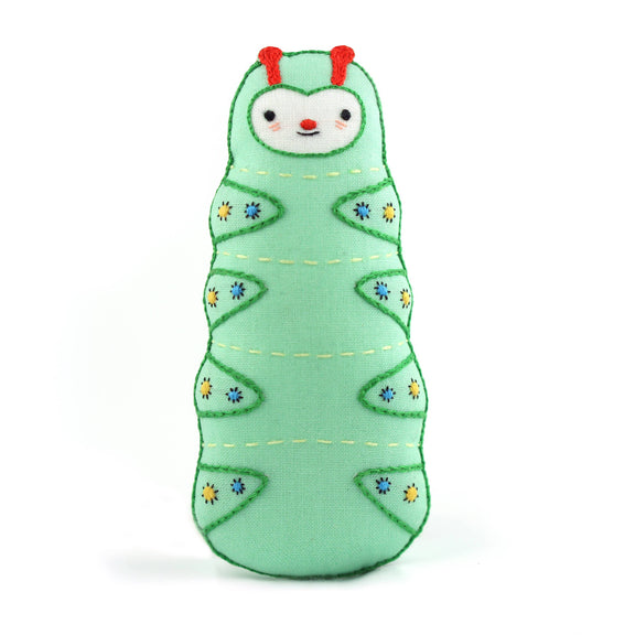 Green caterpillar plush toy with red antennae on a white background