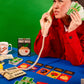 Person playing a card game with a green background, holding cards and using a phone.