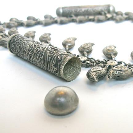 Silver necklace with leaf shaped charms and geometric pendant, close up on chain