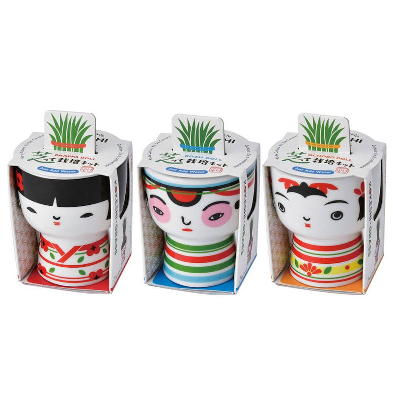 Three colorful ceramic dolls in packaging on a white background