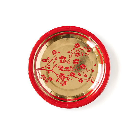Gold plate with red floral design on a red rim against a white background