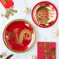 Red and gold paper plates with dragon design on a marble surface.