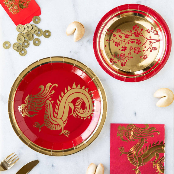 Red and gold paper plates with dragon design on a marble surface.