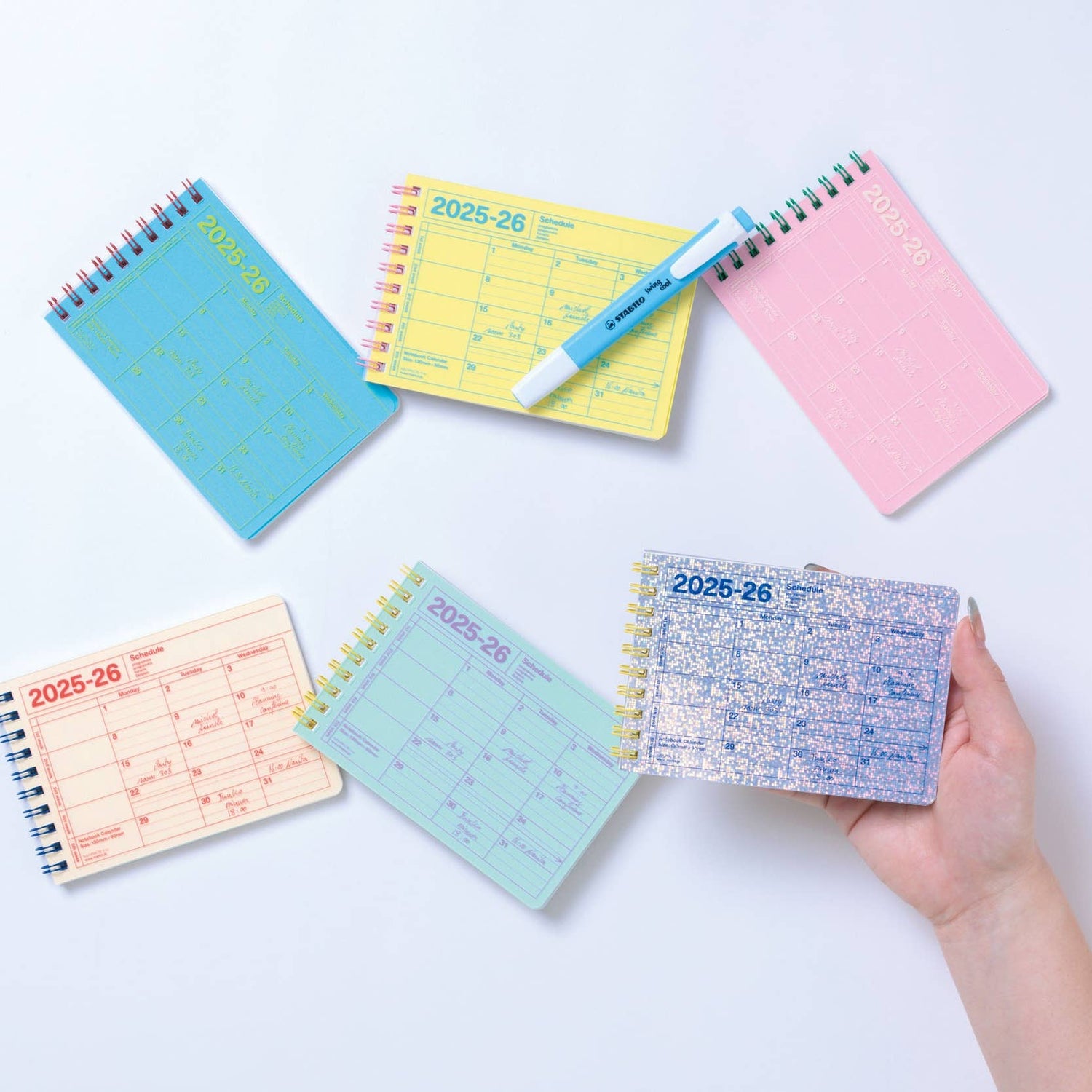 Collection of colorful planners and a pen on a light blue background
