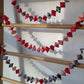 Decorative banner with red, black, and white flags hanging on a wooden ladder against a white wall.