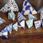Origami triangles with blue and white patterns on a wooden surface