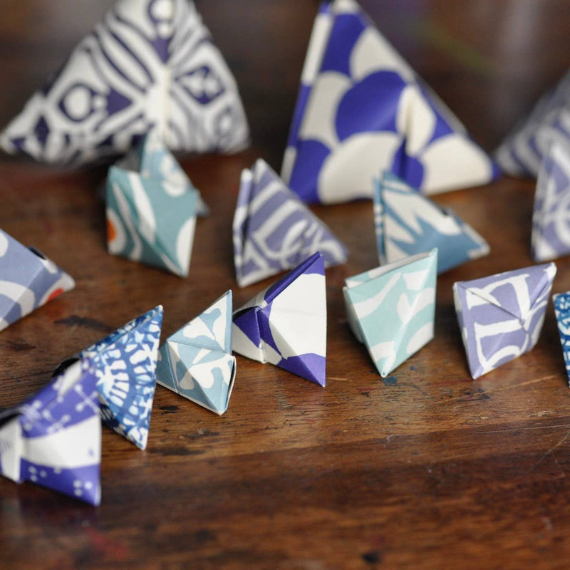 Origami triangles with blue and white patterns on a wooden surface