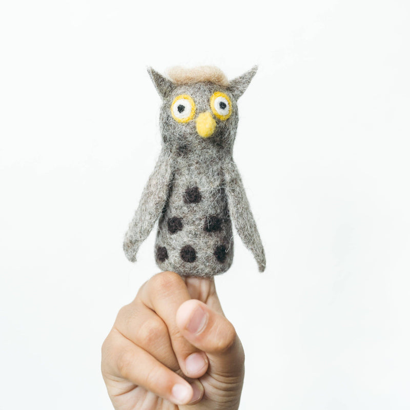 Hand holding a small owl-shaped finger puppet against a white background