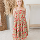 Young girl in a floral dress standing in a room with decorative elements.
