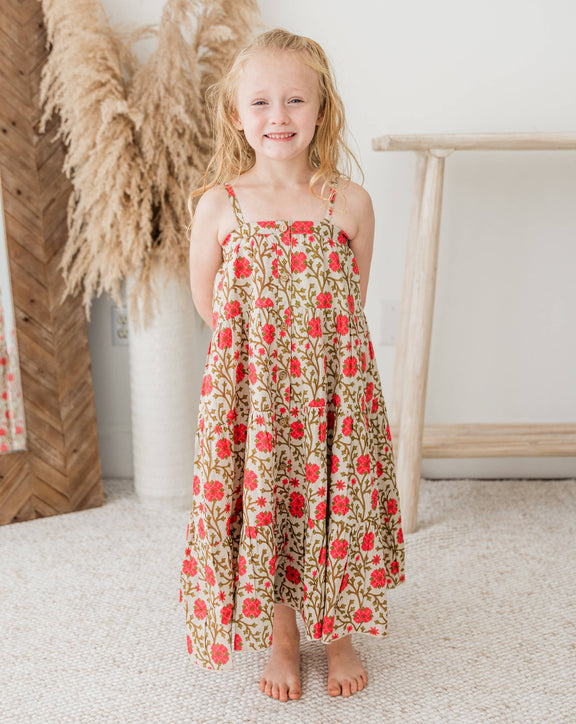 Young girl in a floral dress standing in a room with decorative elements.