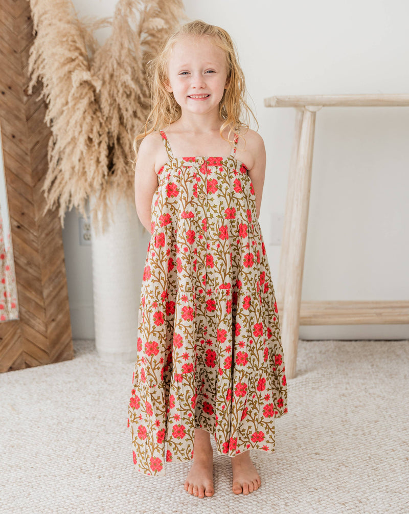 Young girl in a floral dress standing in a room with decorative elements.
