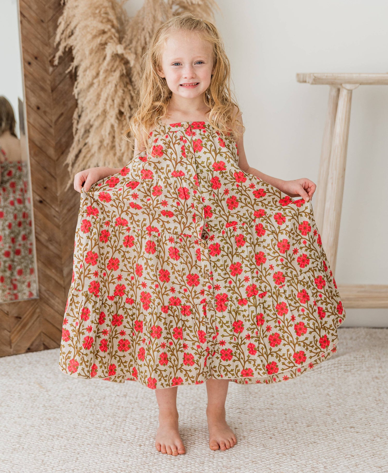 Young girl wearing a floral dress with red flowers in a home setting
