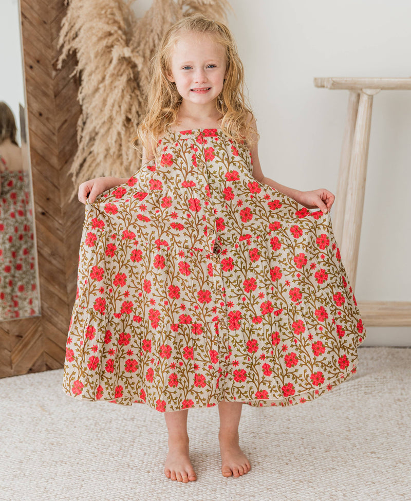 Young girl wearing a floral dress with red flowers in a home setting
