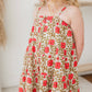 Child wearing a floral dress with red flowers on a neutral background