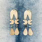 Pair of gold earrings with teardrop and crescent moon shapes on a textured blue background