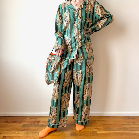 Person wearing a green and gold patterned pajama set on a wooden floor.