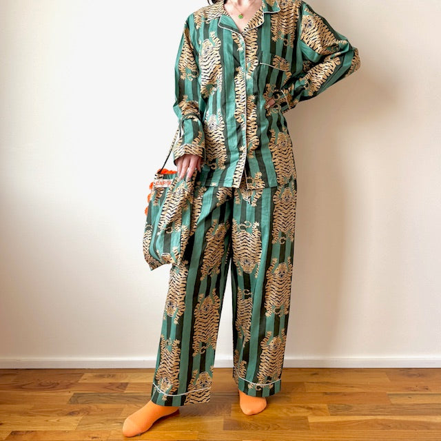 Person wearing a green and gold patterned pajama set on a wooden floor.