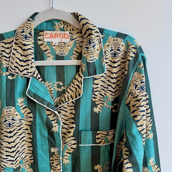 Teal pajama set with tiger pattern on a hanger against a white background