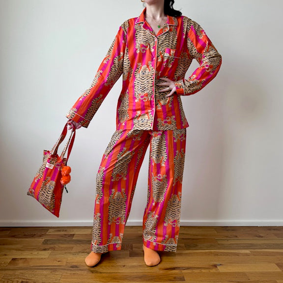 Person wearing a colorful patterned outfit holding a matching bag on a wooden floor.