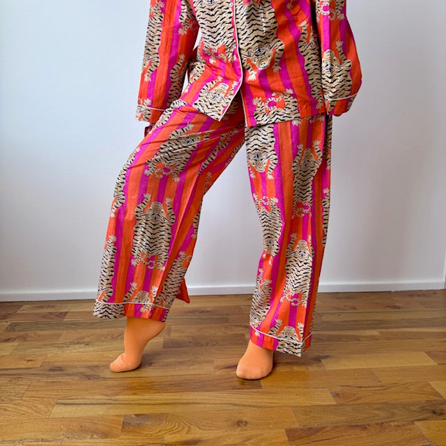Person wearing a colorful patterned outfit on a wooden floor.