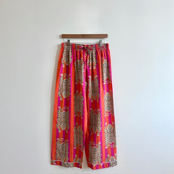 Colorful patterned pants hanging on a rack against a white background