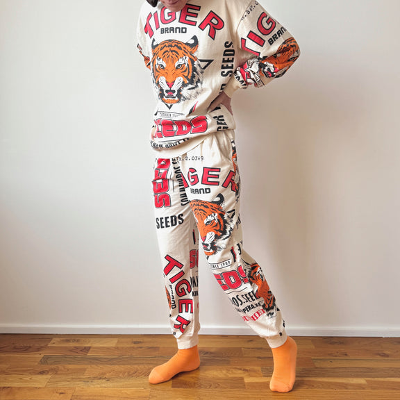 Person wearing a pajama set with tiger and brand logo designs on a plain background