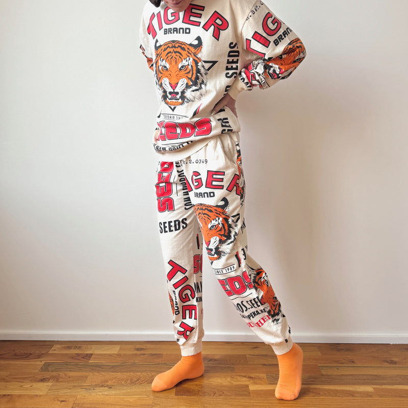 Person wearing a pajama set with tiger and brand logo designs on a plain background
