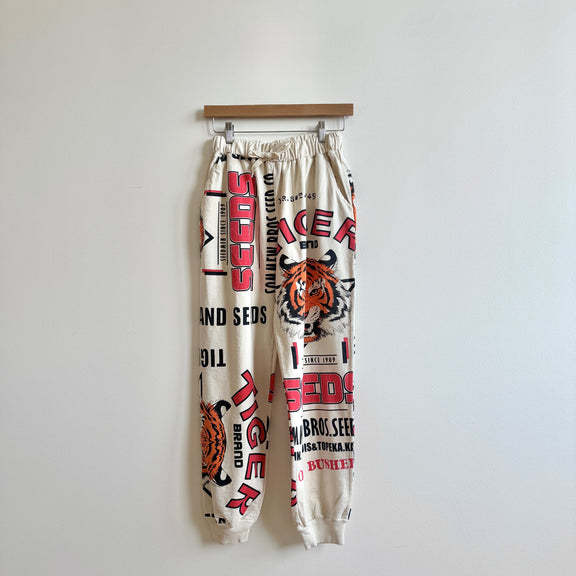 Beige sweatpants with tiger print and text on a white background