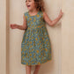 Child wearing a floral dress standing against a plain background