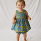 Child wearing a blue and yellow floral dress on a white background