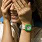 Person wearing a green watch with a striped shirt, covering their face with their hands.