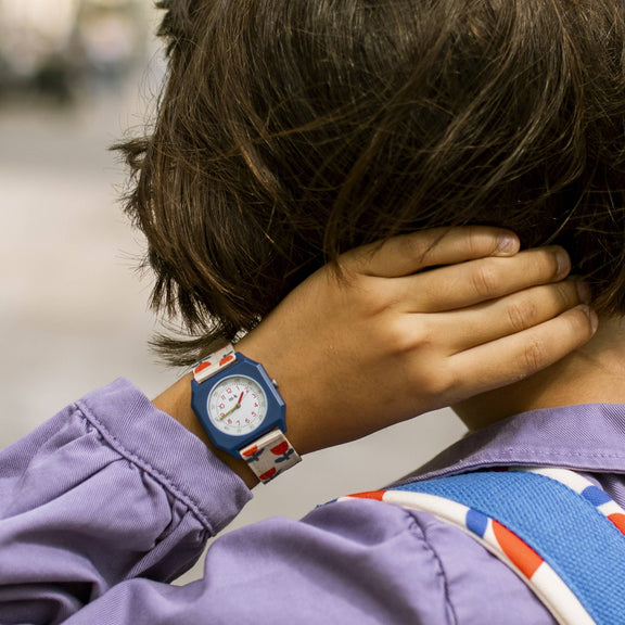 Person wearing a purple jacket with a colorful strap over their shoulder, covering part of their face.
