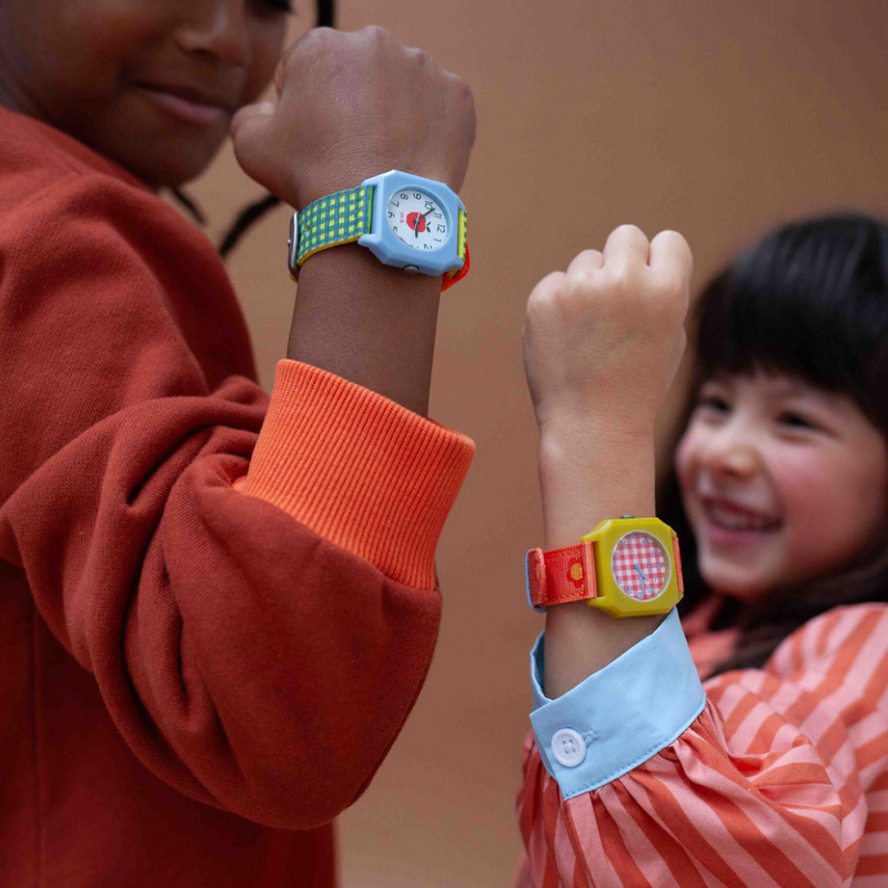 Two children wearing colorful digital wristbands on a plain background