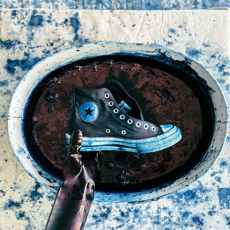 Black Converse shoe with blue laces in a rusted metal sink