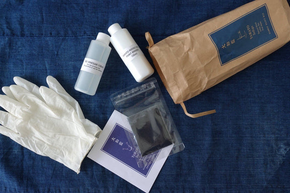 Cosmetic products including bottles, gloves, and a pouch on a blue denim background